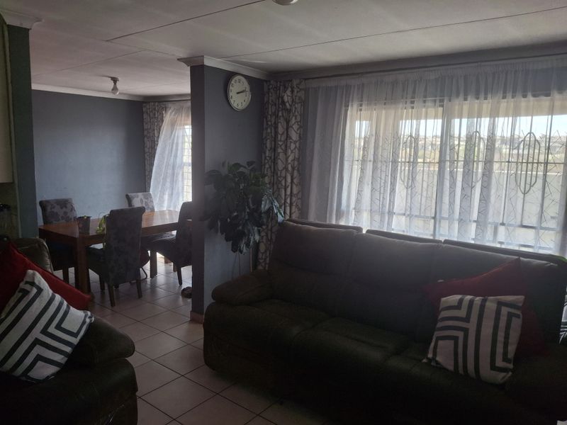 Open plan living and dining area featuring tiled flooring and large sliding glass doors with security bars, providing natural light and access to the exterior.
