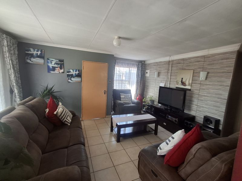 A living room featuring tiled flooring, coved ceilings, and a combination of painted and wallpapered feature walls.