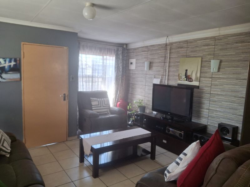 A functional living room featuring tiled flooring and decorative wall finishes, providing a comfortable space for relaxation and entertainment.