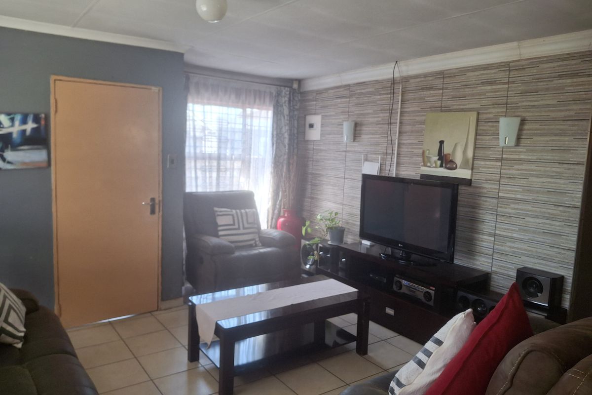 A functional living room featuring tiled flooring and decorative wall finishes, providing a comfortable space for relaxation and entertainment.