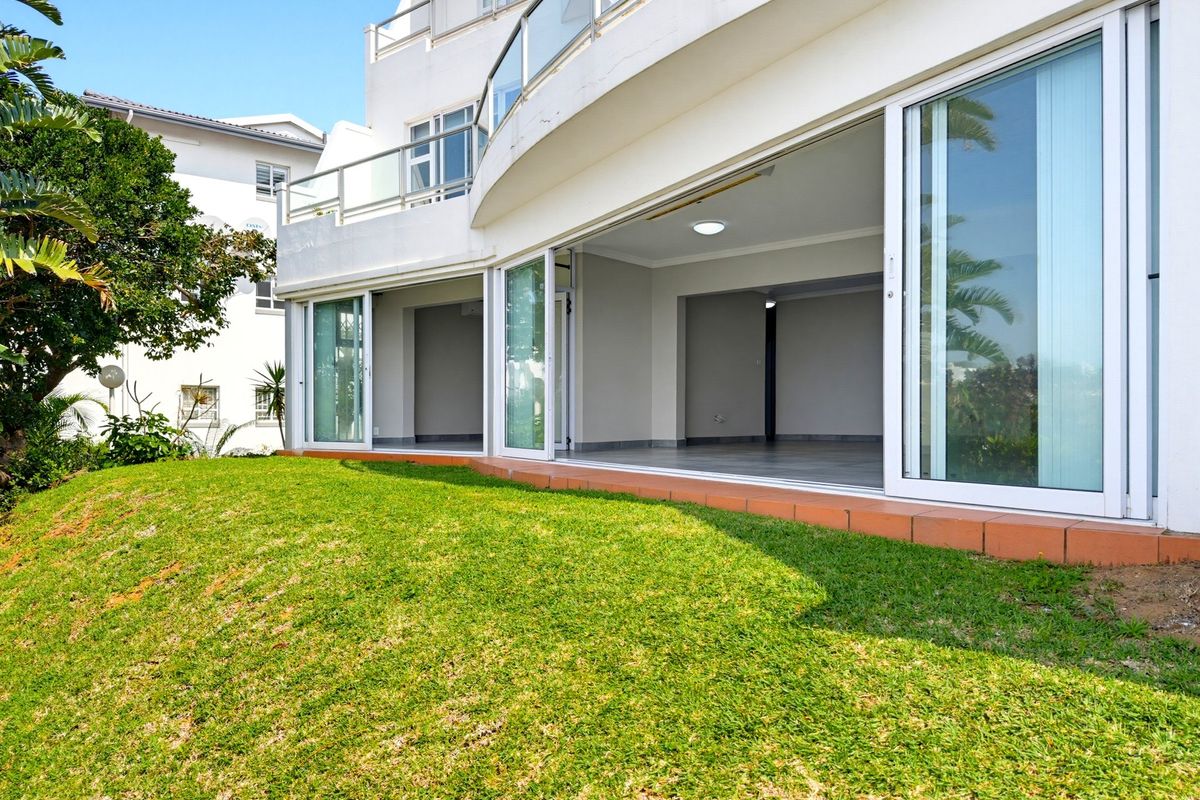 A view of the rear exterior featuring a spacious tiled patio with large sliding glass doors leading into an open-plan living area.