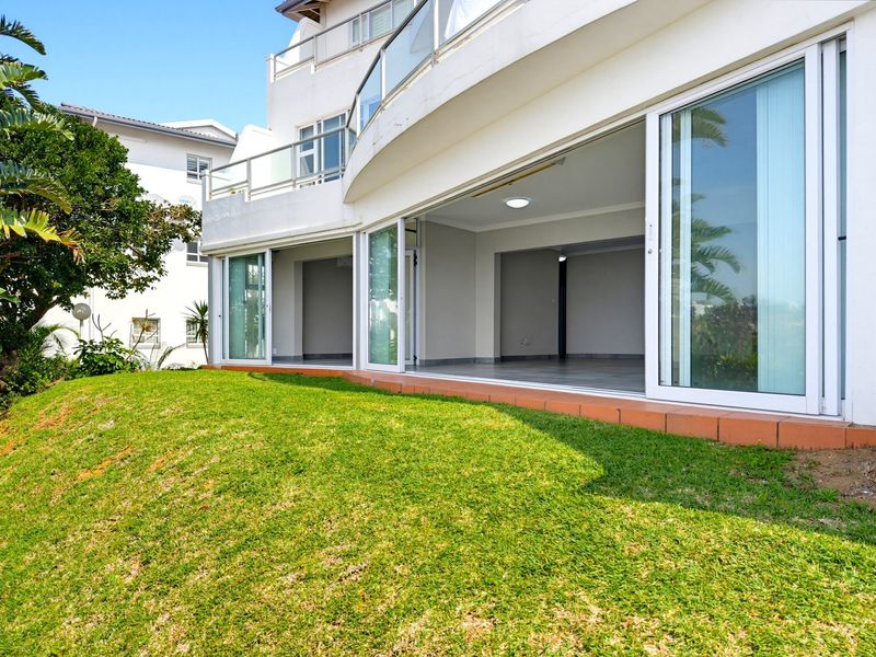 A view of the rear exterior featuring a spacious tiled patio with large sliding glass doors leading into an open-plan living area.