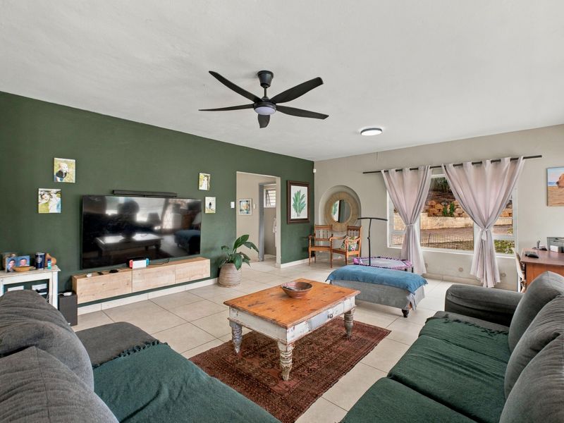 Spacious living room featuring tiled flooring, a ceiling fan, and a decorative recessed wall niche, providing a comfortable and functional family living space.