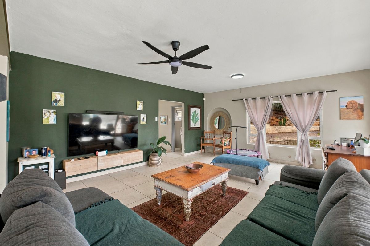Spacious living room featuring tiled flooring, a ceiling fan, and a decorative recessed wall niche, providing a comfortable and functional family living space.
