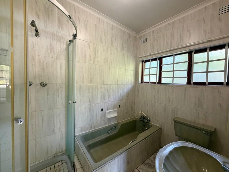 A dated bathroom featuring a built-in bathtub, separate shower enclosure, and pedestal basin with neutral wall tiling.