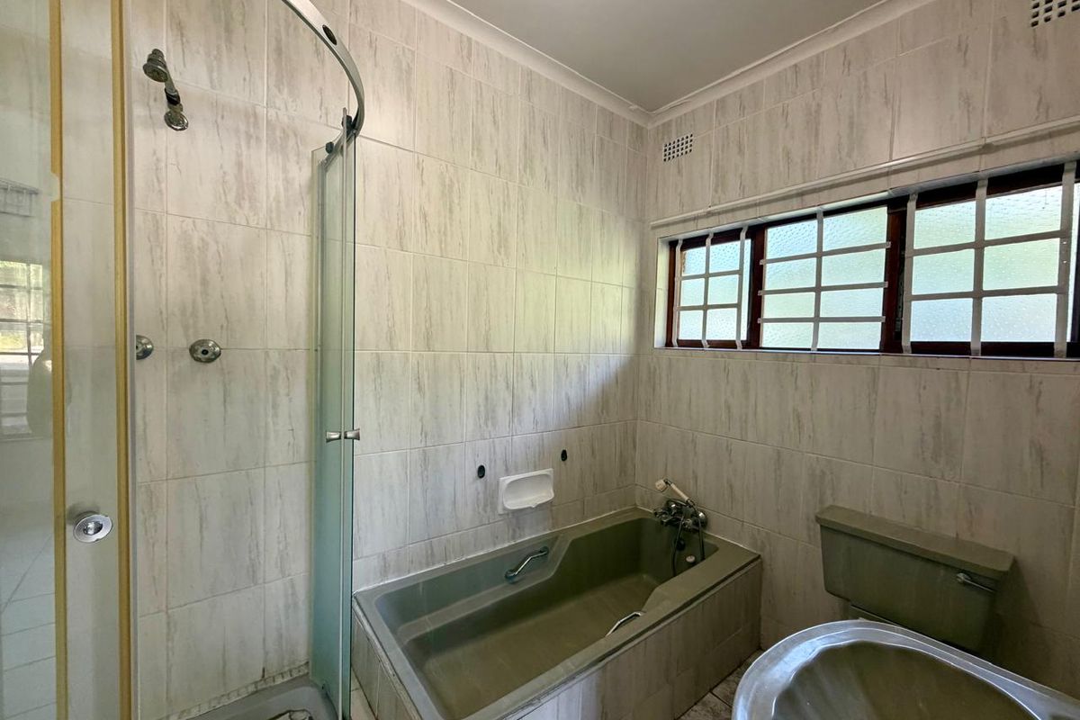 A dated bathroom featuring a built-in bathtub, separate shower enclosure, and pedestal basin with neutral wall tiling.