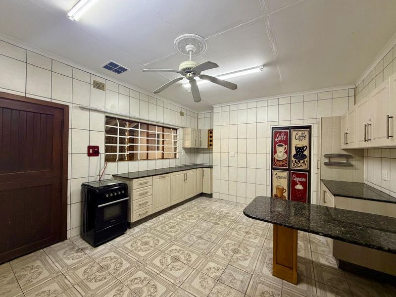 A functional kitchen featuring granite countertops, built-in cabinetry, a freestanding stove, and tiled finishes throughout.