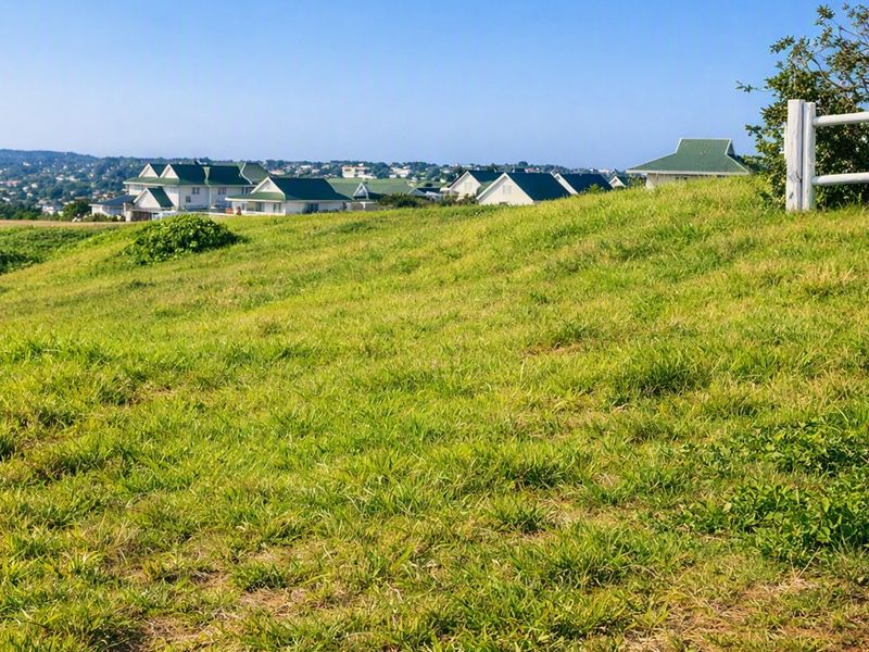 A view of the surrounding residential landscape from the vacant land, featuring a post and rail fence boundary.