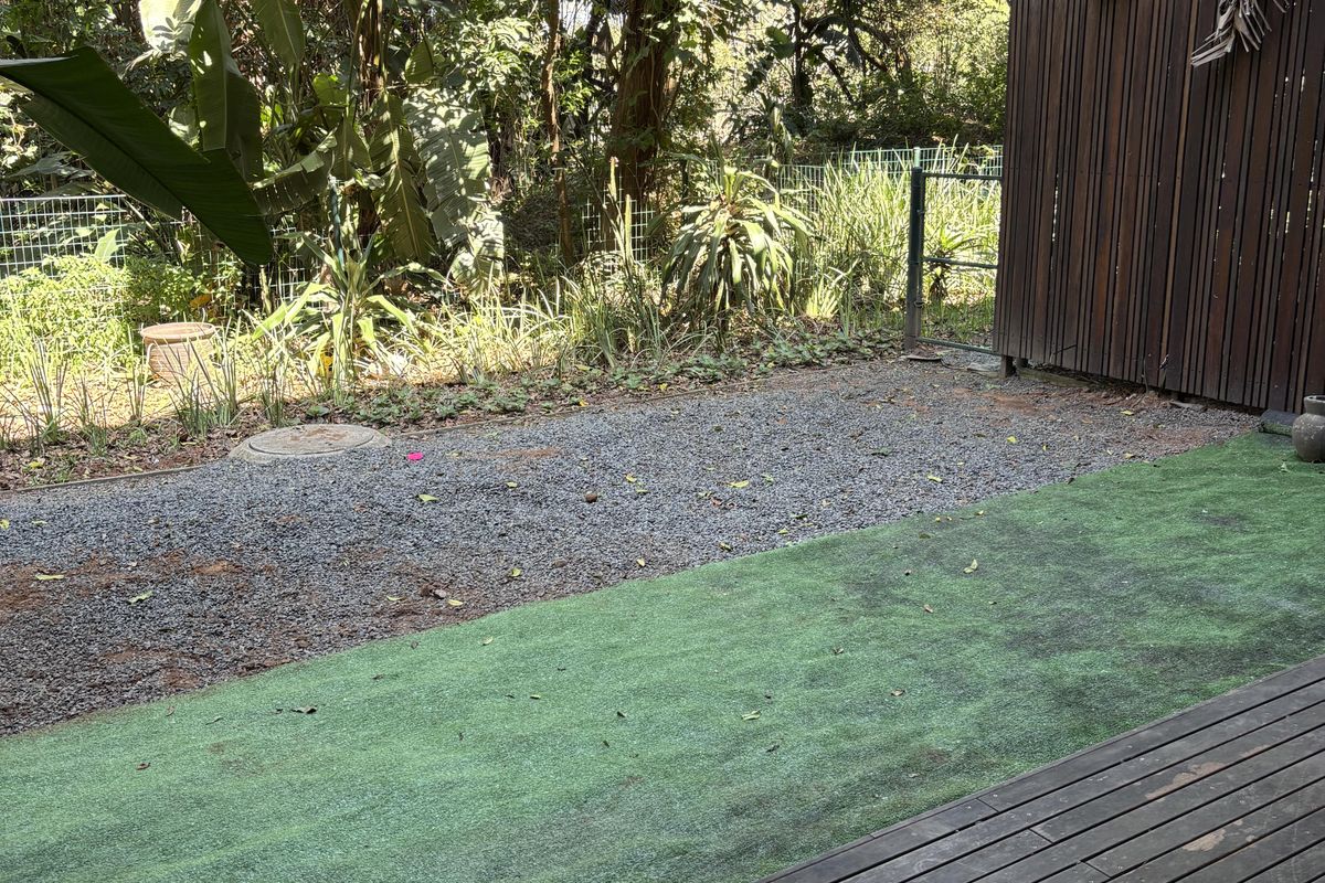 A private rear outdoor space featuring timber decking, a section of artificial turf, a gravel area, and a timber privacy screen.