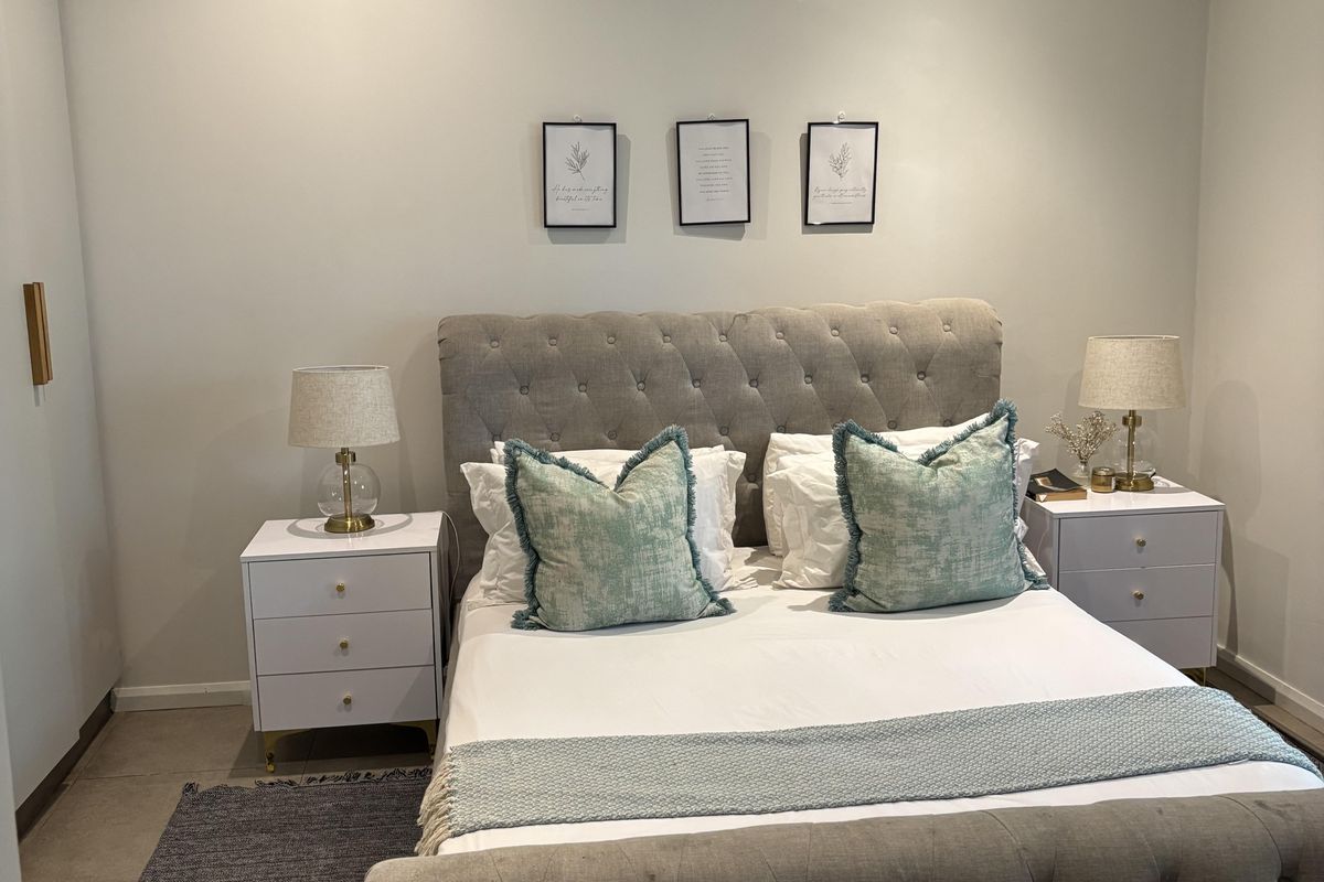 A well-maintained bedroom featuring tiled flooring, a ceiling fan, and a wall-mounted split-system air conditioner.