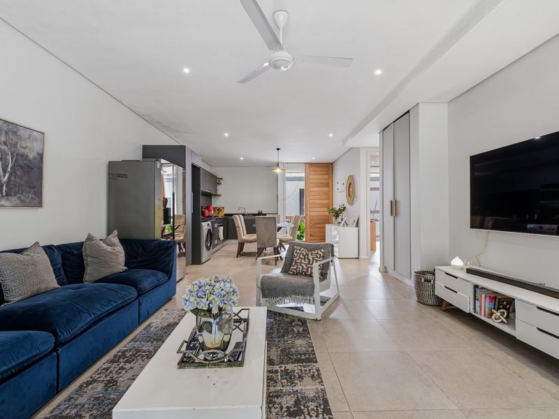 Spacious open-plan living and kitchen area featuring modern tiled flooring, recessed lighting, a ceiling fan, and ample built-in cabinetry.