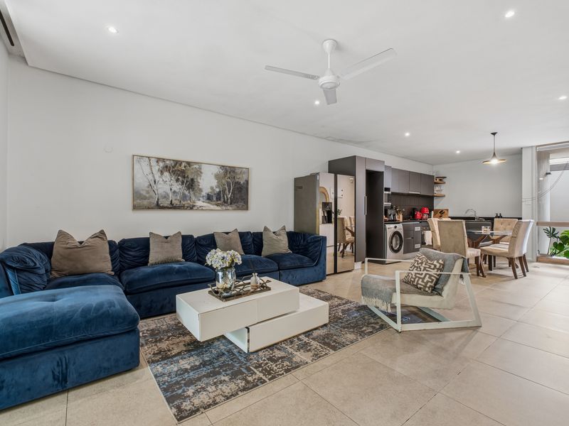 Spacious open-plan living area featuring tiled floors, recessed lighting, a ceiling fan, and a modern integrated kitchen with built-in cabinetry and appliances.