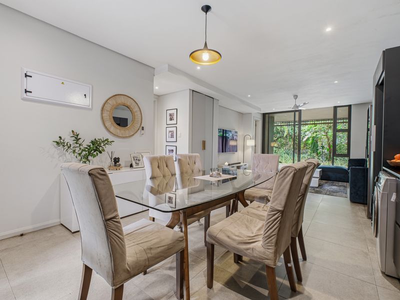 Modern open-plan dining and living area featuring tiled floors, recessed lighting, and large sliding glass doors leading to an outdoor space.