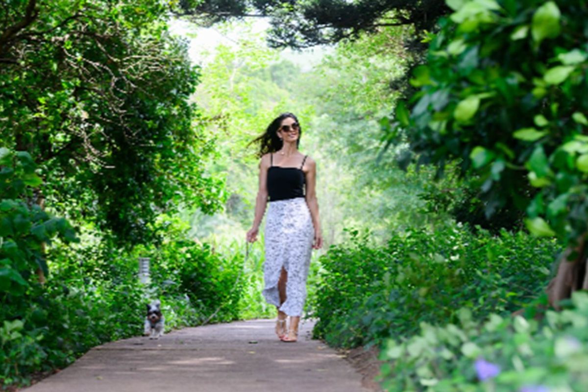 A scenic, well-maintained garden pathway surrounded by lush mature trees and established greenery, offering a peaceful outdoor walking area.