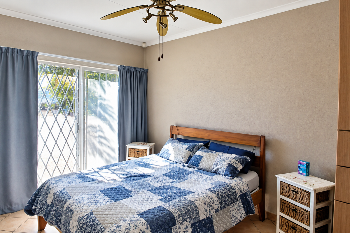A bedroom featuring tiled flooring, a ceiling fan, built-in wardrobe, and a sliding glass door with security gate providing access to the exterior.