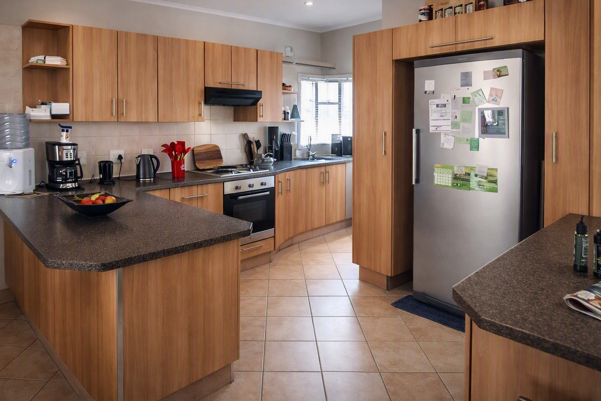 A functional kitchen featuring wood-look laminate cabinetry, dark laminate countertops, built-in oven with gas hob, and tiled flooring throughout.
