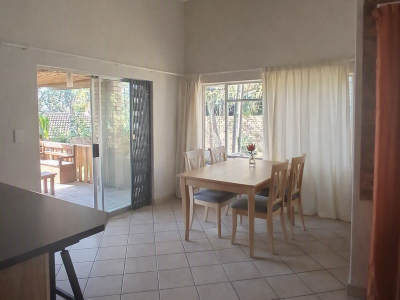 Open plan dining area featuring tiled flooring and large sliding glass doors providing direct access to the outdoor patio space.