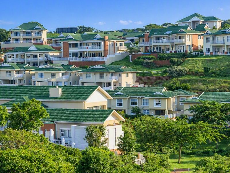 An elevated aerial view of a residential estate featuring multiple homes with green tiled roofs set within a landscaped, terraced environment.