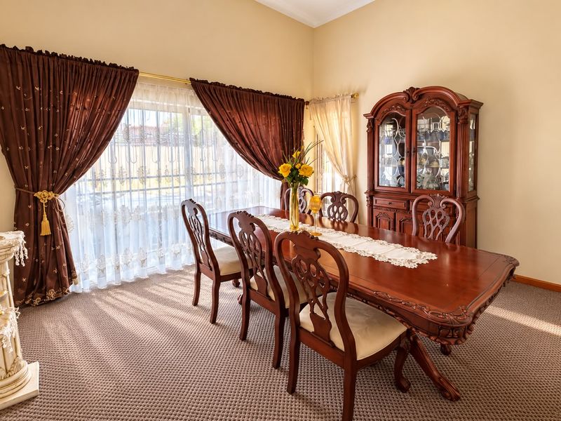 A formal dining room featuring carpeted flooring, a sliding glass door with curtains, and decorative cove cornicing.