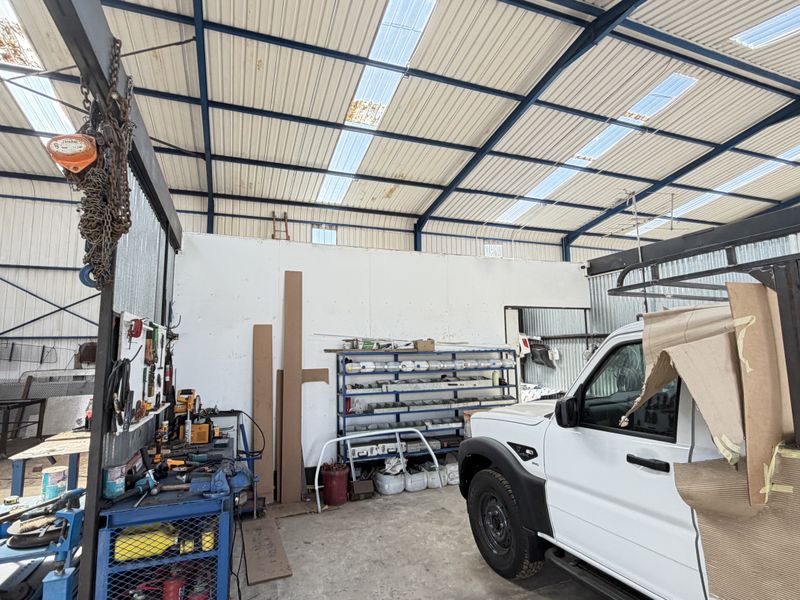 A large industrial utility space or workshop featuring a steel portal frame, corrugated metal roofing with translucent panels, and concrete flooring.