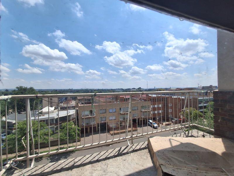 An elevated balcony featuring a metal balustrade and concrete flooring, offering an open view of the surrounding residential neighborhood.