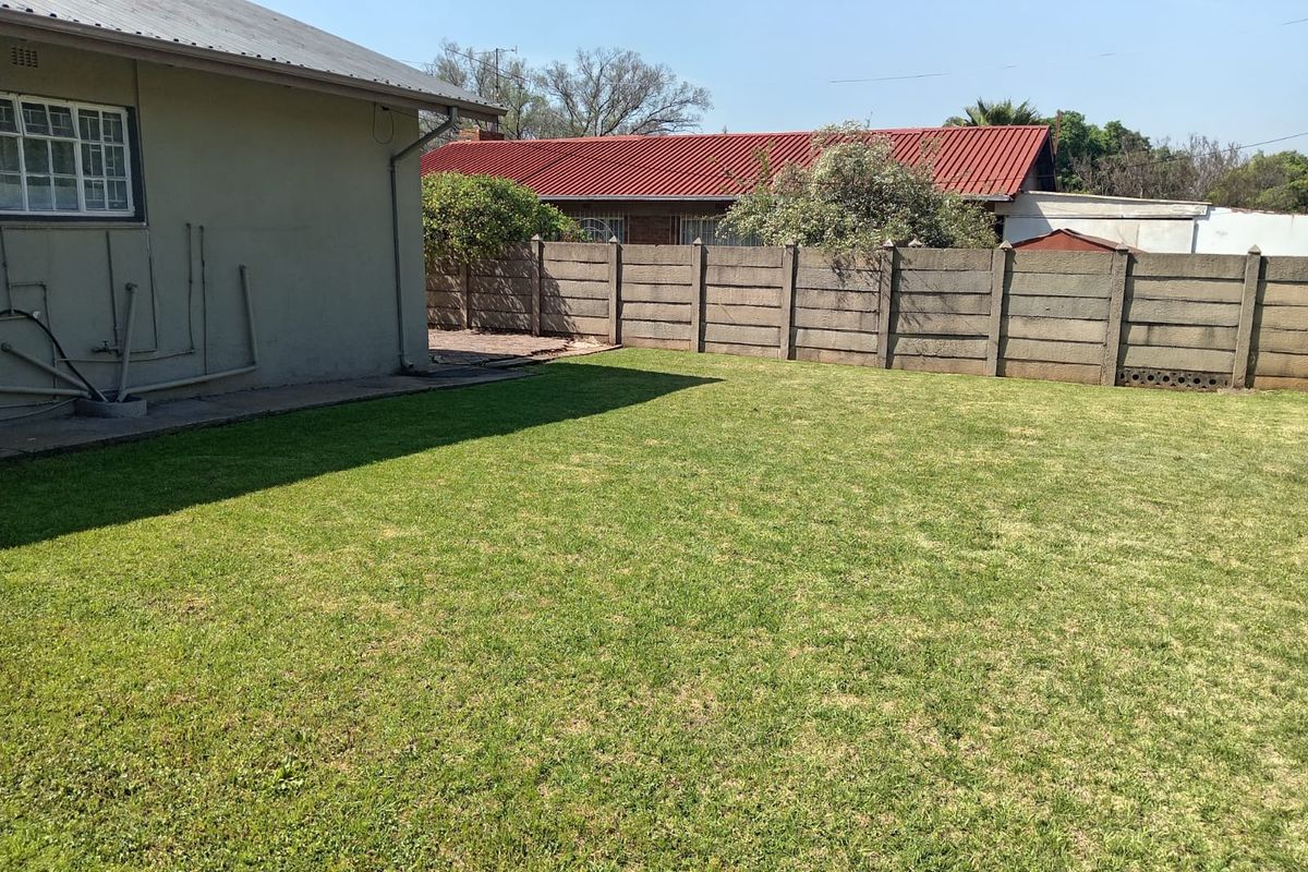 A spacious rear garden featuring a well-maintained lawn, enclosed by a precast concrete boundary wall and adjacent to the rear building elevation.