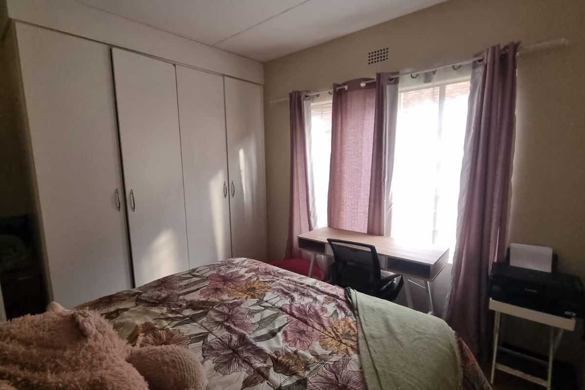 A functional bedroom featuring built-in cupboards and a large window that allows for natural light.