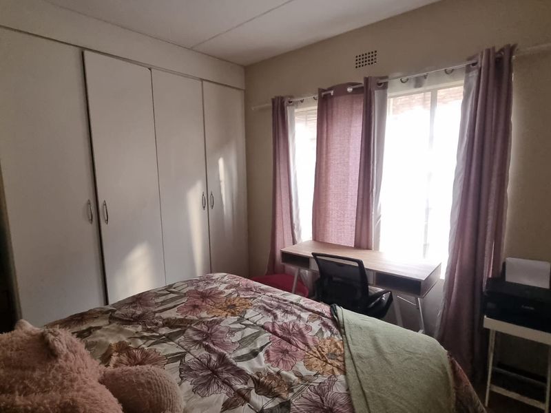 A functional bedroom featuring built-in cupboards and a large window that allows for natural light.
