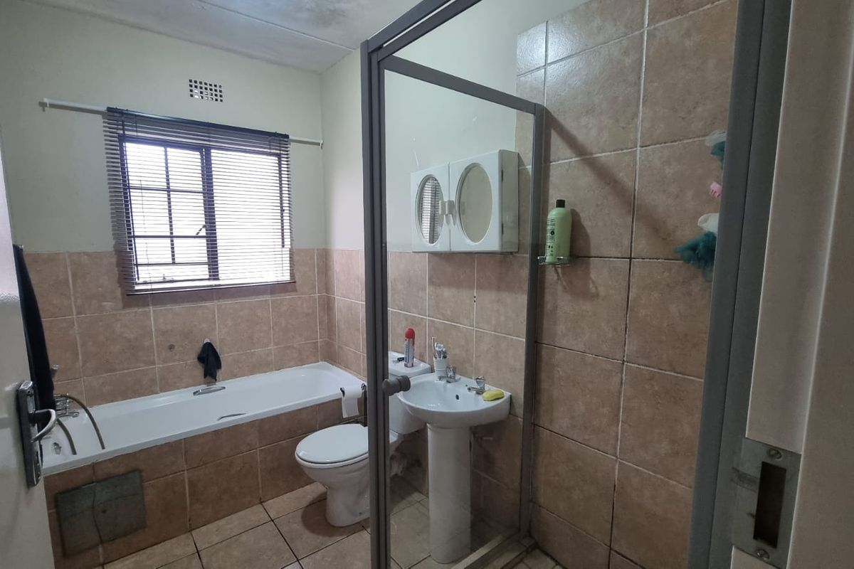 A dated bathroom featuring a bathtub, pedestal sink, toilet, and a separate shower enclosure with tiled finishes throughout.