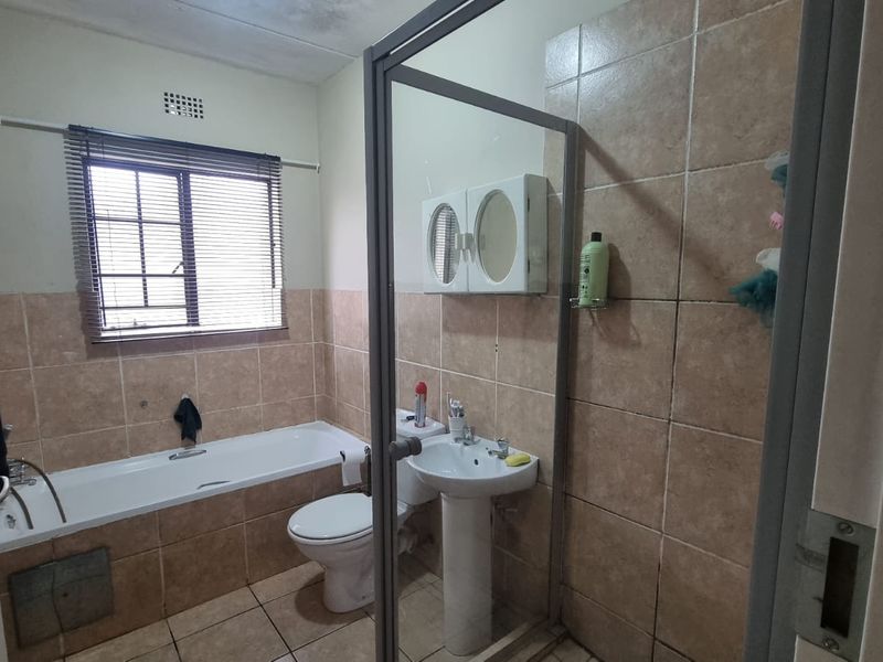 A dated bathroom featuring a bathtub, pedestal sink, toilet, and a separate shower enclosure with tiled finishes throughout.