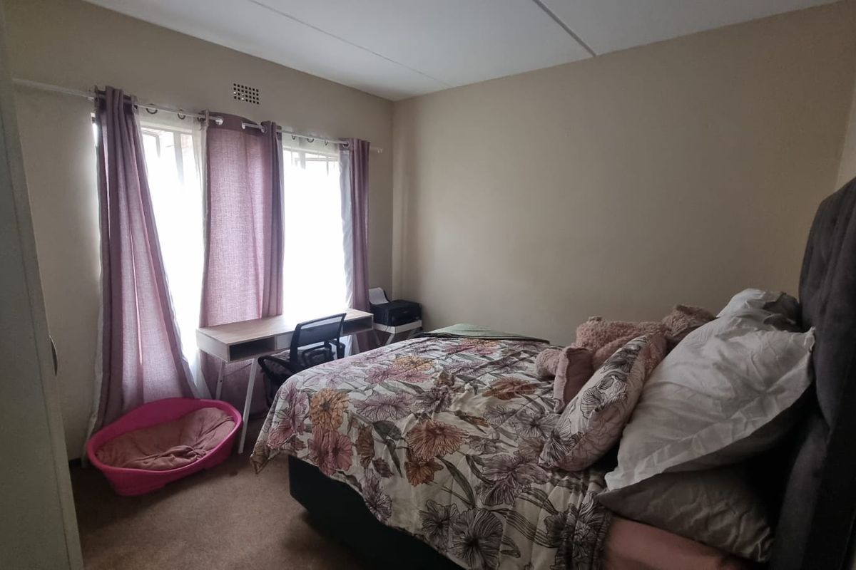 A standard bedroom featuring carpeted flooring and a ventilation grille, providing a functional space for rest.