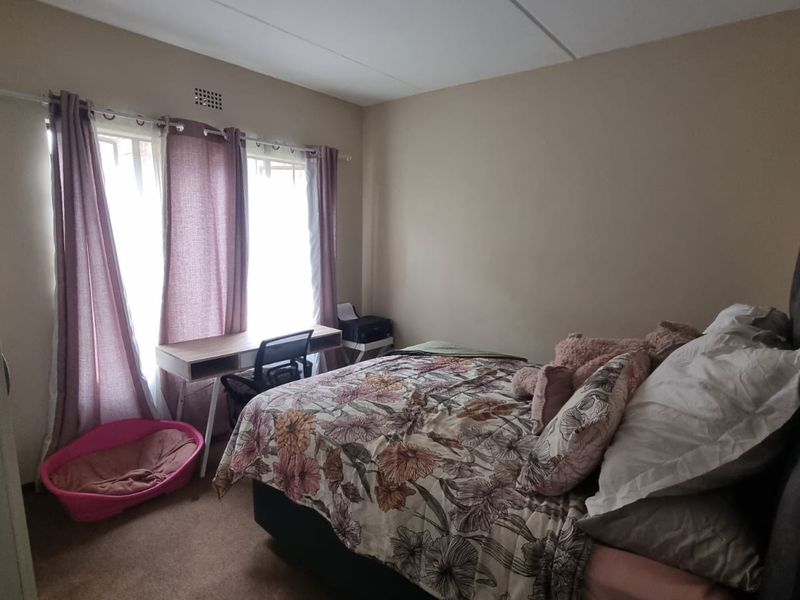 A standard bedroom featuring carpeted flooring and a ventilation grille, providing a functional space for rest.