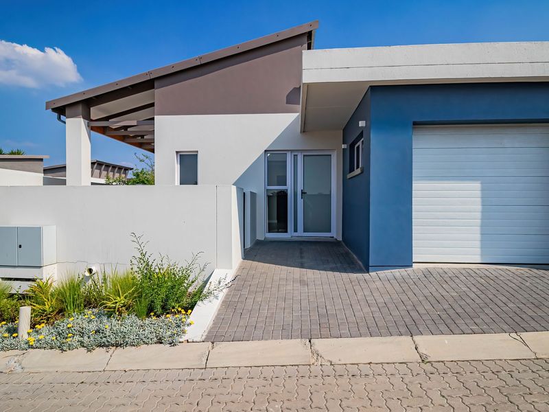 Modern townhouse exterior featuring a paved driveway, single garage, and clean architectural lines with a contemporary blue and white facade.