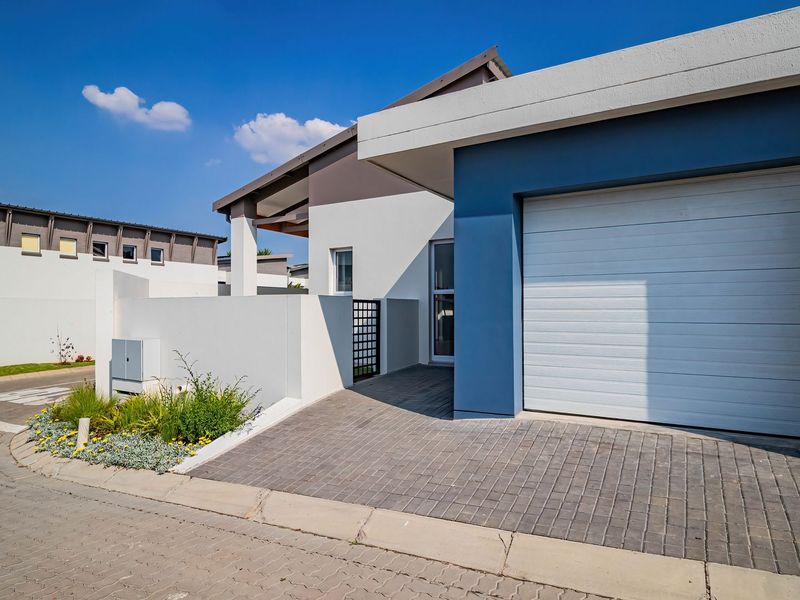 Modern townhouse exterior featuring a clean facade, a single garage with a sectional door, and a paved driveway entrance.