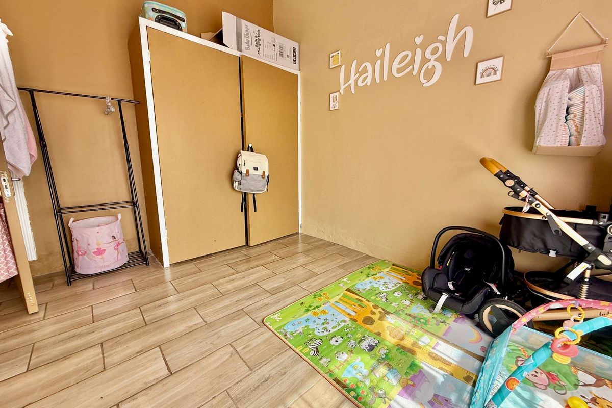 A bedroom featuring tiled flooring and a built-in wardrobe, currently utilized as a nursery space.