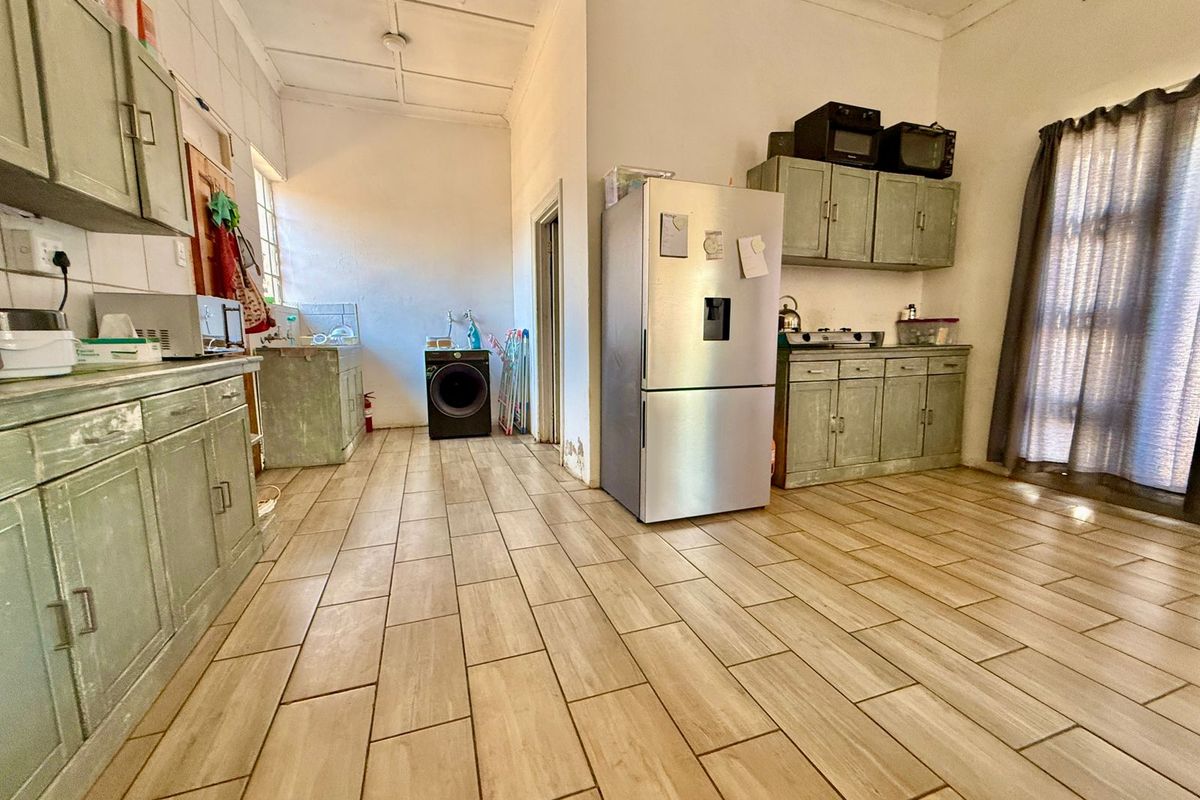 A functional kitchen space featuring tiled flooring, built-in cabinetry, and dedicated plumbing connections for laundry appliances.