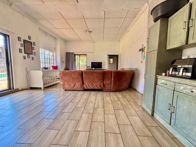 Spacious open-plan living area featuring wood-look tiled flooring, built-in cabinetry, and sliding glass doors leading to the exterior.