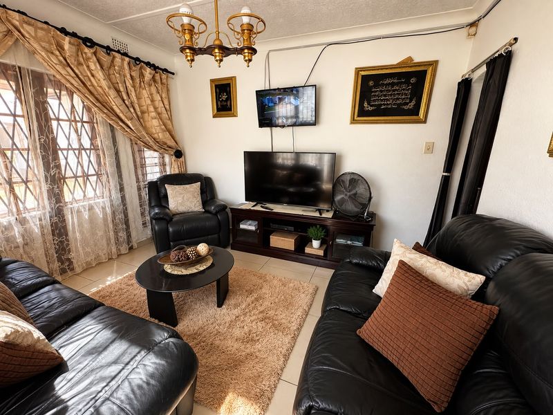 A comfortable living room featuring tiled flooring and security bars on the windows, providing a functional and lived-in space.