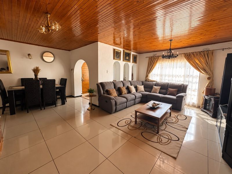 Spacious open-plan living and dining area featuring polished porcelain floor tiles and a warm timber tongue and groove ceiling with arched architectural details.
