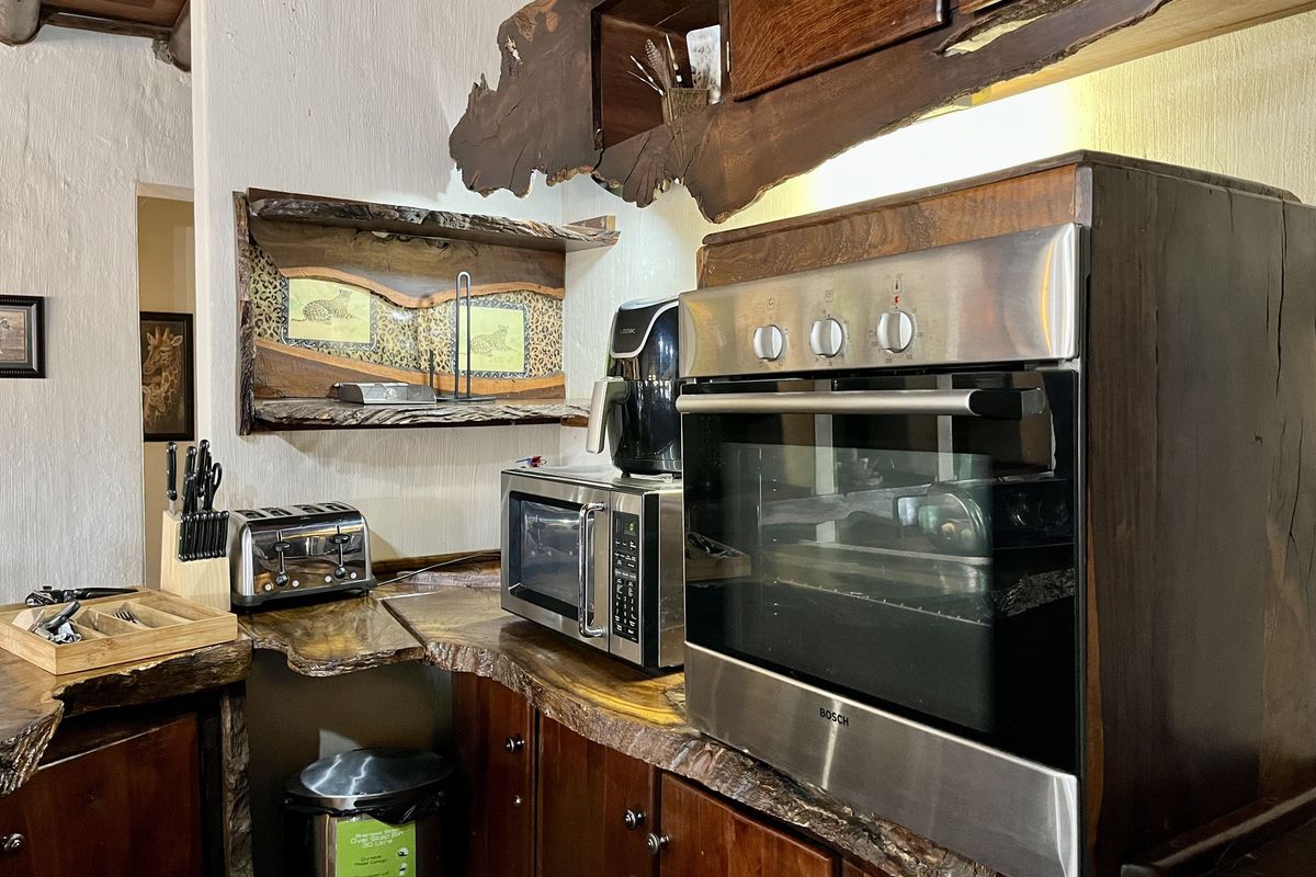 A rustic kitchen area featuring custom live-edge wooden countertops, integrated cabinetry, and a built-in stainless steel oven.