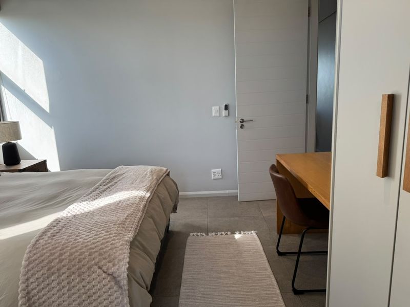 A well-maintained bedroom featuring neutral tiled flooring, a built-in wardrobe, and clean wall finishes, offering a bright and functional living space.