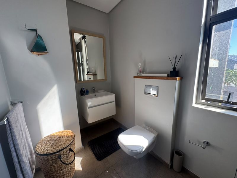 Modern guest bathroom featuring a wall-mounted vanity, wall-hung toilet with concealed cistern, and neutral tiled flooring with natural light.
