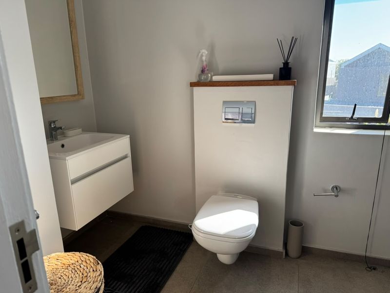 Modern bathroom featuring a wall-hung vanity, wall-hung toilet with concealed cistern, and neutral tiled flooring.