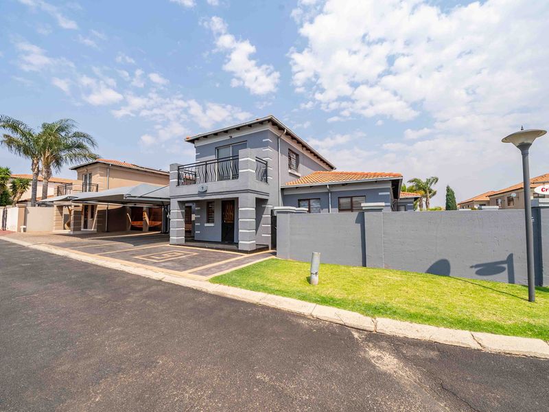 A well-maintained double-storey house featuring a paved driveway, carport, and a private balcony, situated within a secure residential estate.