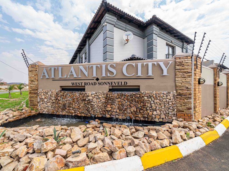 Entrance signage and water feature for Atlantis City residential complex, featuring stone cladding and secure boundary wall with electric fencing.
