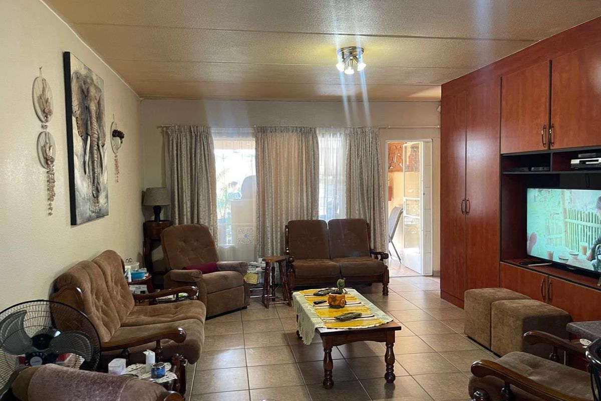 A living room featuring tiled flooring and extensive built-in wooden cabinetry, providing ample storage and a dedicated space for a television.