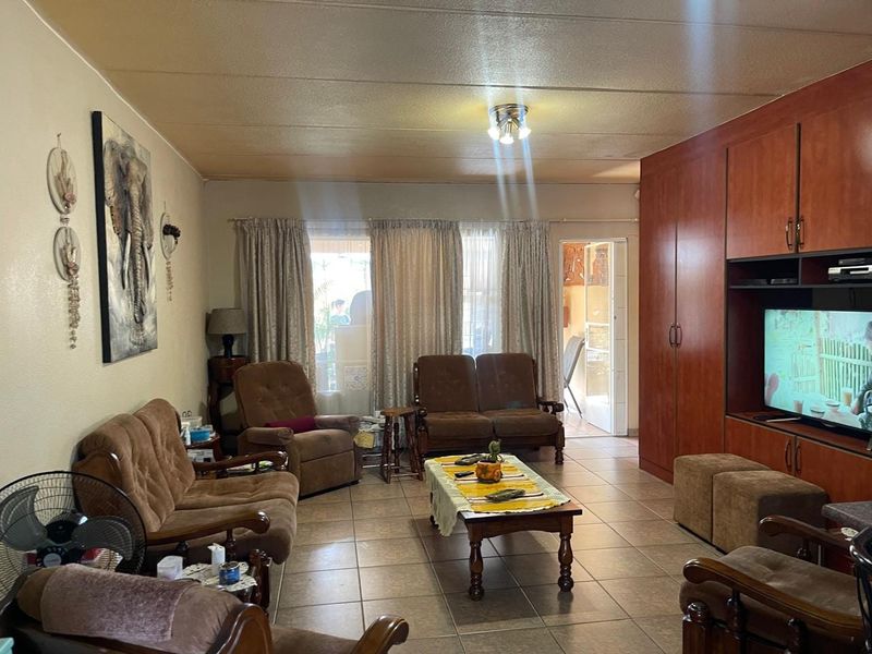 A living room featuring tiled flooring and extensive built-in wooden cabinetry, providing ample storage and a dedicated space for a television.