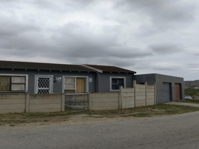 Front exterior view of a single-story house featuring a tiled roof, security-barred windows, a precast concrete boundary wall, and an attached double garage.