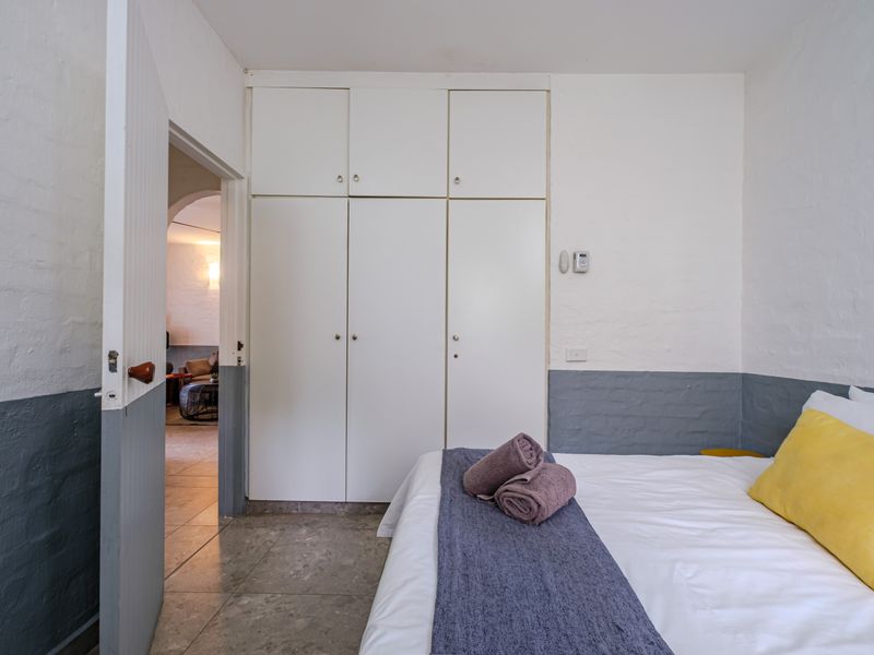 A bedroom featuring built-in cupboards, tiled flooring, and painted brick walls with a two-tone finish.