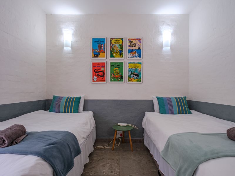 A well-maintained bedroom featuring twin beds, tiled flooring, and wall-mounted lighting.